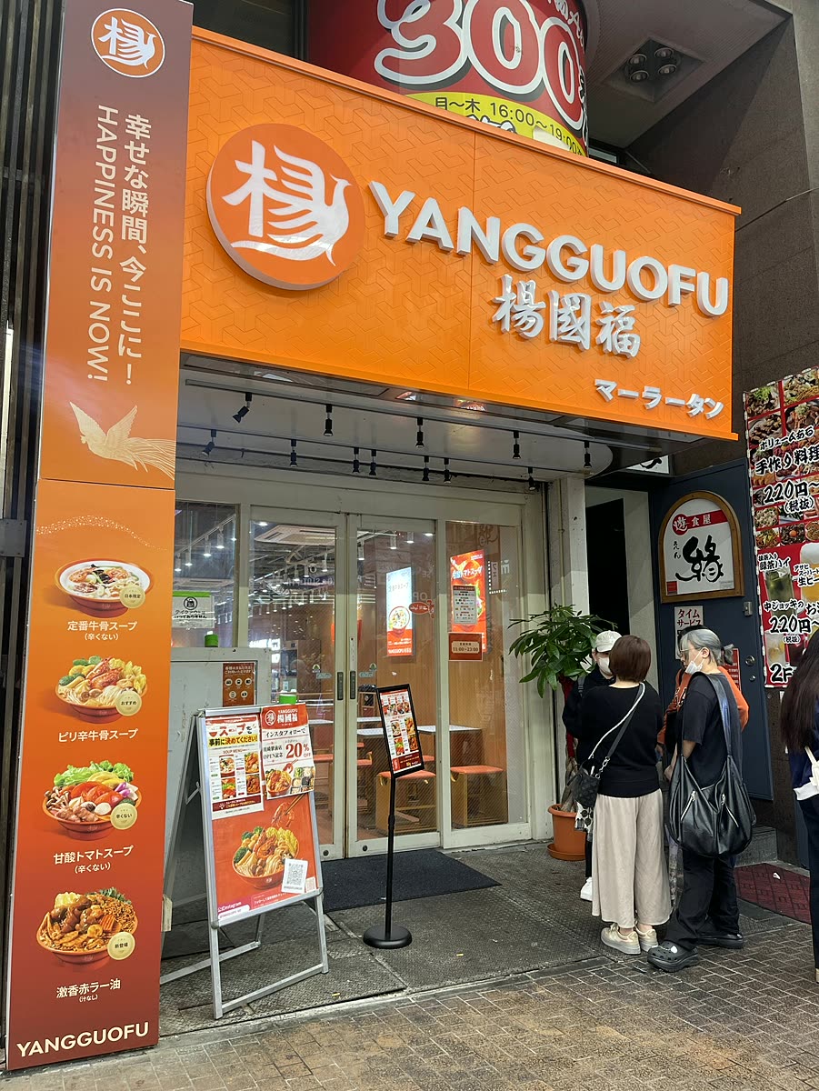 楊國福マーラータン川崎駅前店のオレンジ色の外観と幸せな瞬間今ここにの看板