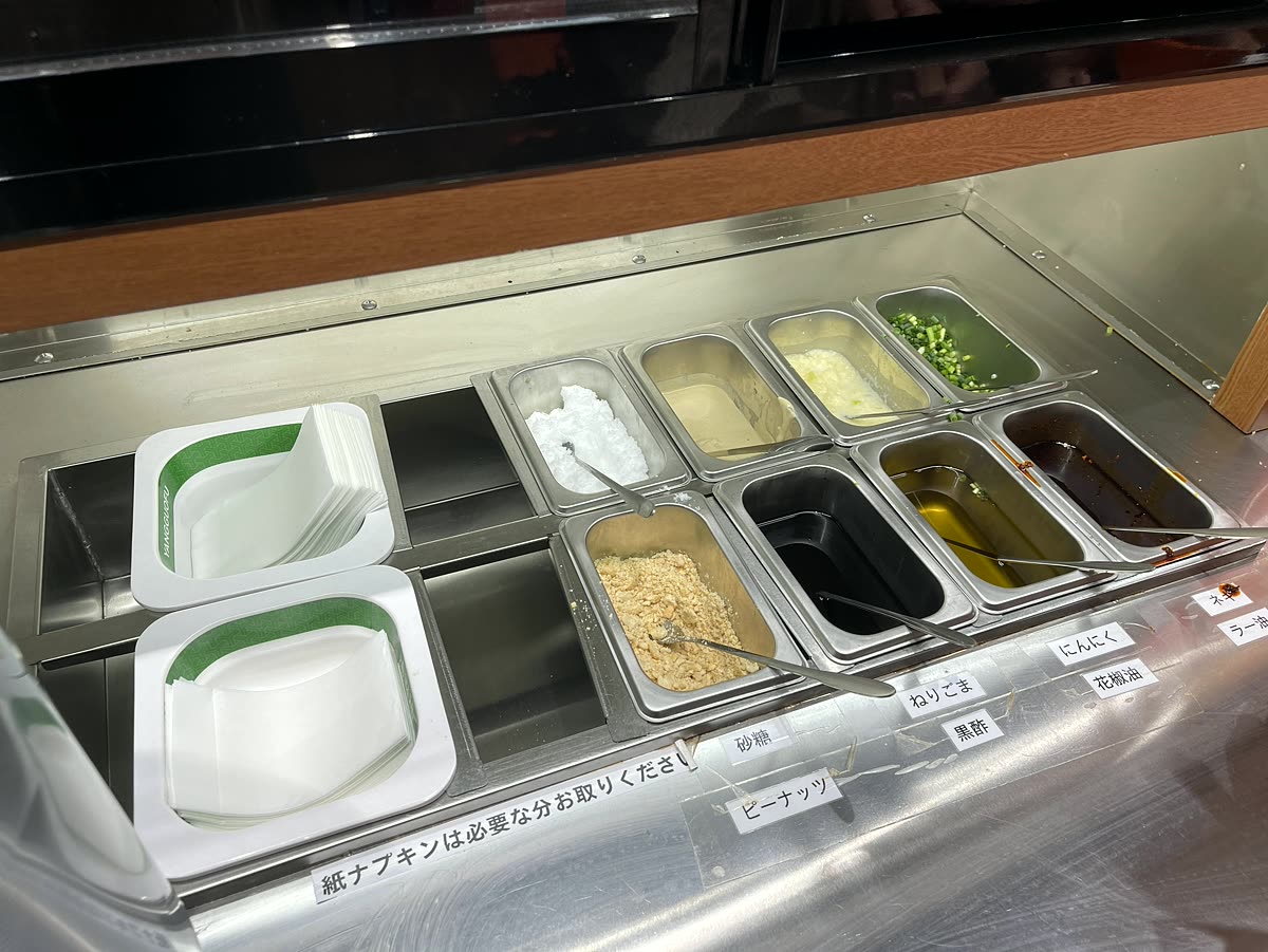 ピーナッツや砂糖ねぎにんにくラー油などが並ぶセルフ調味料コーナー