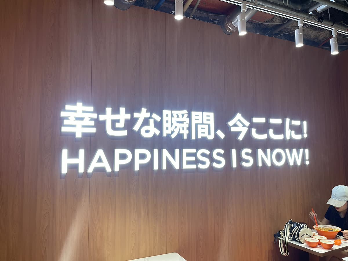 幸せな瞬間今ここにHAPPINESS IS NOWと書かれた店内の壁の照明看板