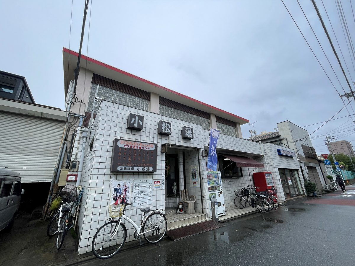白いタイルの建物に「小松湯」の大きな文字看板が掲げられた小松湯の外観