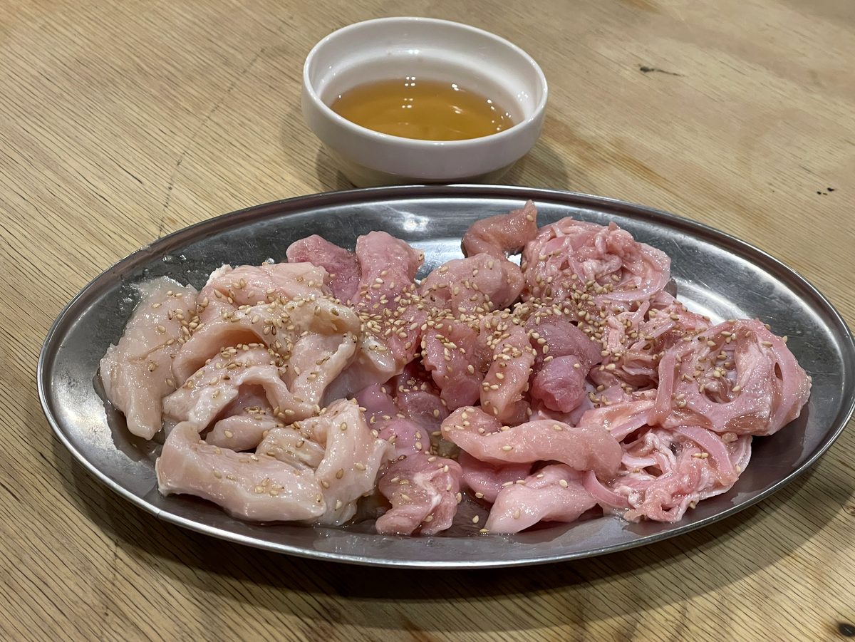 ごまを振った生ホルモンの盛り合わせ、2種類の部位が並ぶ皿
