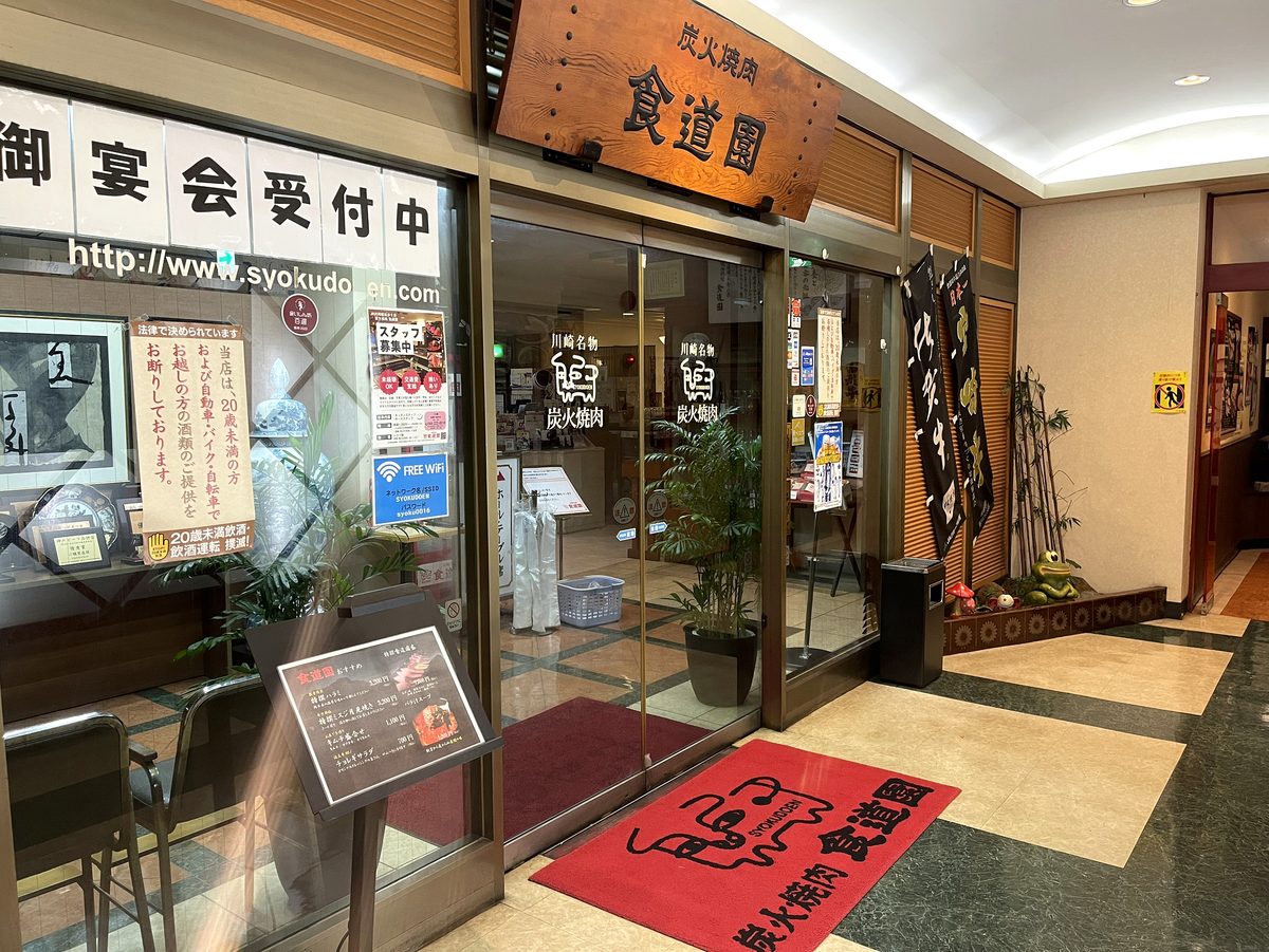 ビルの2階入口にある炭火焼肉食道園の看板と赤いウェルカムマット