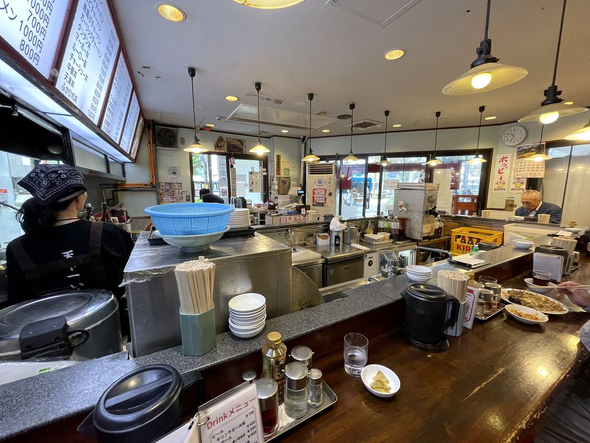 天龍の年季の入った店内カウンター、提灯のような照明と厨房の様子